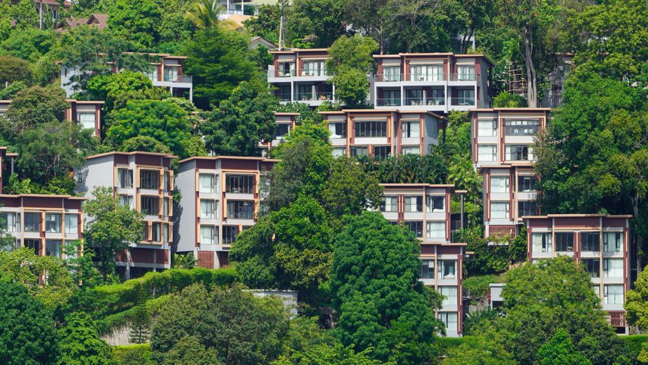 Tropical villas nestled on a lush hillside in Phuket, Thailand, showcasing vibrant greenery.