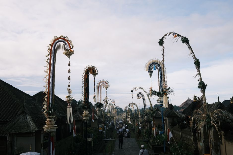 A vibrant Balinese street adorned with festive penjor poles during a cultural celebration.