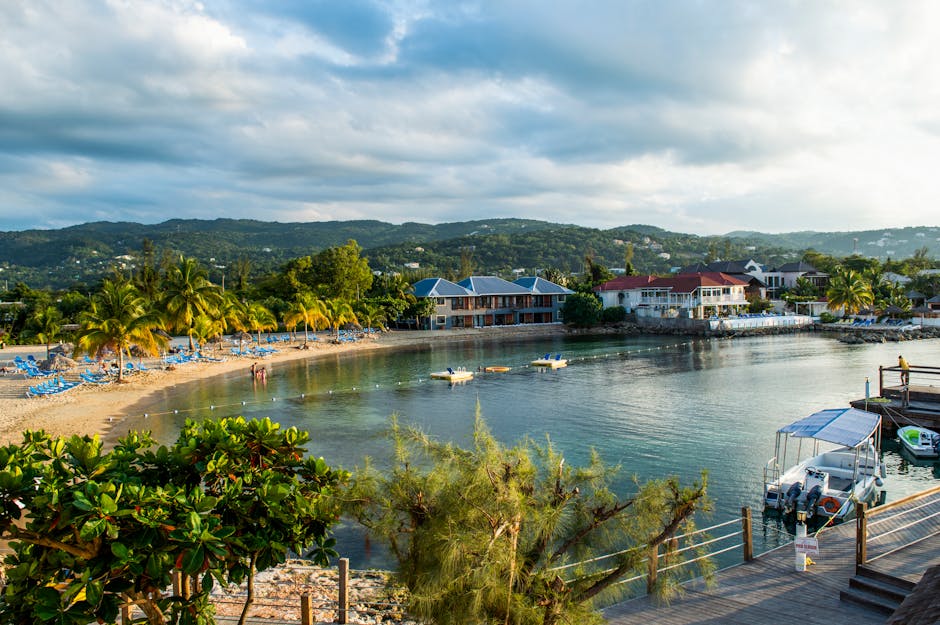 Settlement with cottages near forested mountains situated on sandy beach and pier with trees