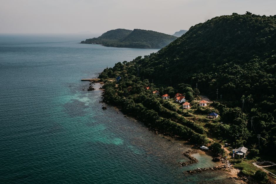 Aerial view of a serene coastal village in Vietnam with lush greenery and calm waters.
