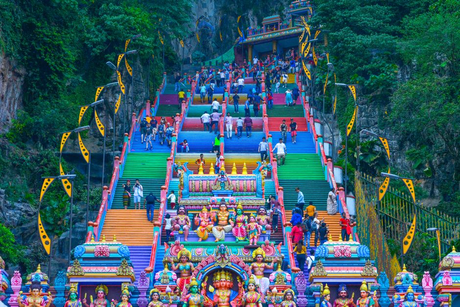 Colorful stairs at Batu Caves, a famous religious site in Malaysia, with tourists exploring the iconic landmark.