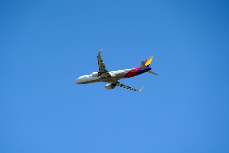 A commercial jet in flight against a bright blue sky, showcasing aviation travel.