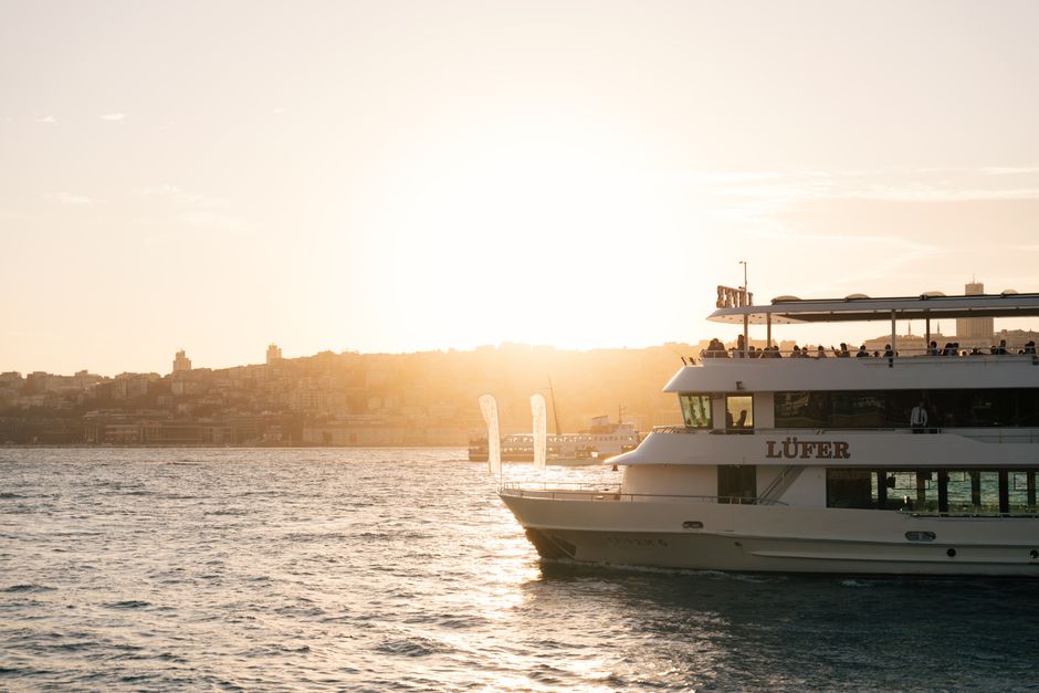 A scenic sunset over a harbor with a cruise ship on the water, offering a tranquil travel experience.