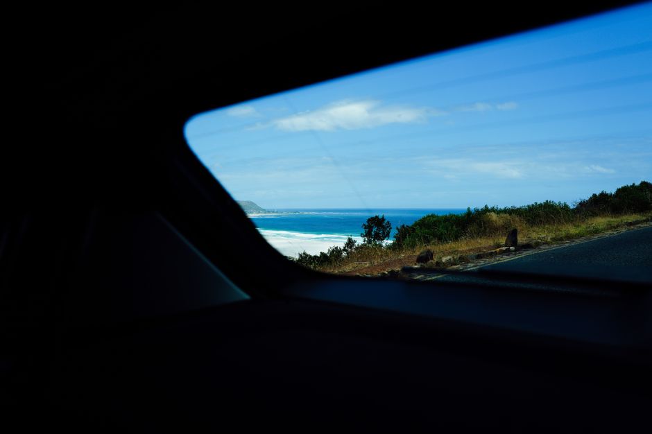 Experience a breathtaking coastal view captured through a car window on a bright, sunny day.