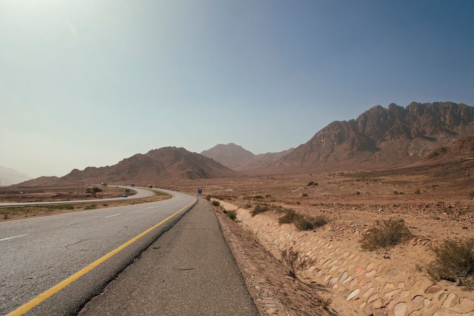 Wide road through desert landscape with mountains, Aqaba, Jordan, captured on a clear day.