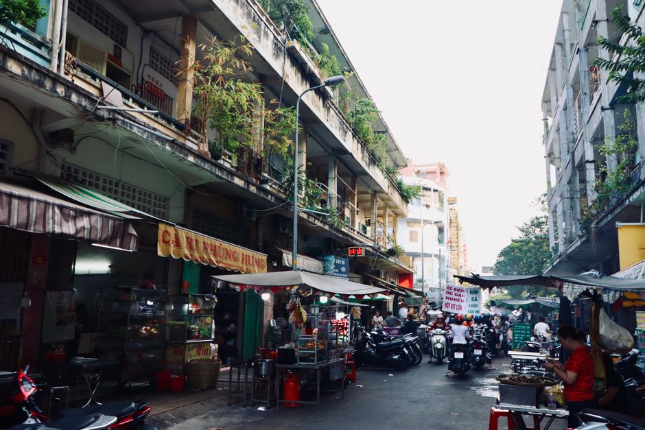 Vibrant street market scene in Southeast Asian city with food stalls and locals.