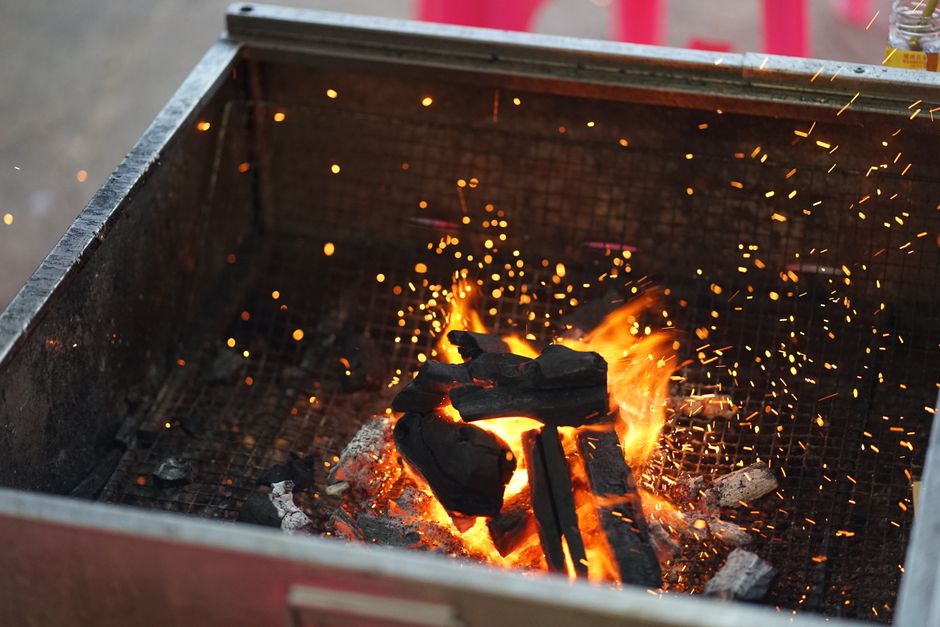 Lively outdoor charcoal grill fire with glowing embers and sparks.