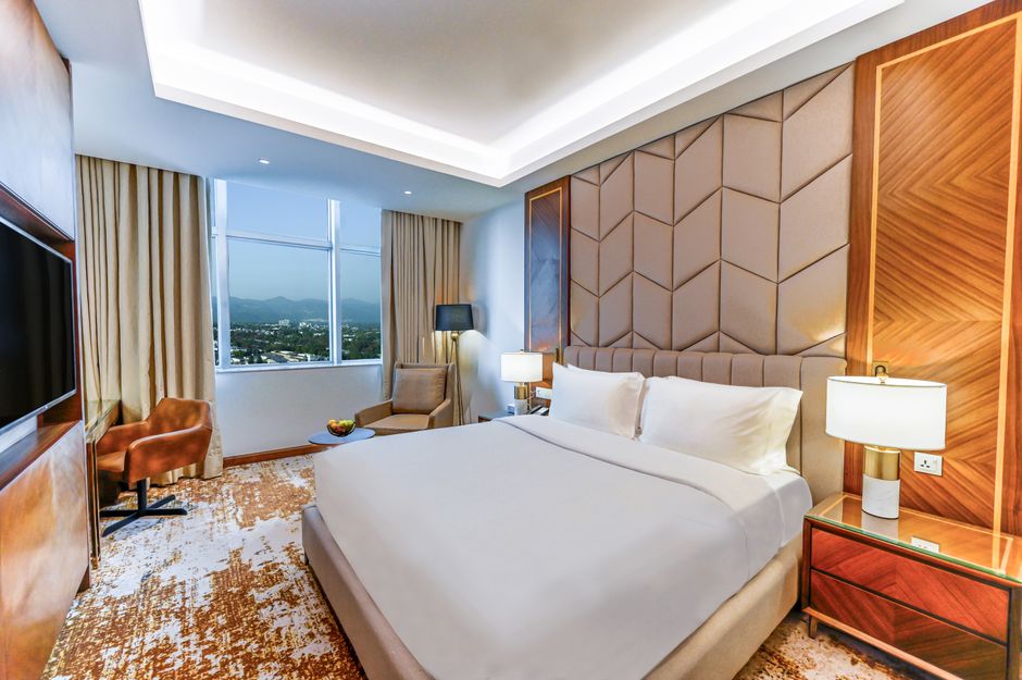Elegant hotel room interior in Islamabad with mountain view, showcasing luxury furnishings.