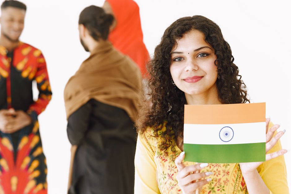 A smiling Indian woman holds the national flag, showcasing cultural attire.