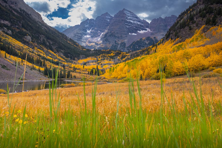 Vibrant fall colors surround Maroon Bells mountain, reflecting in alpine lake.