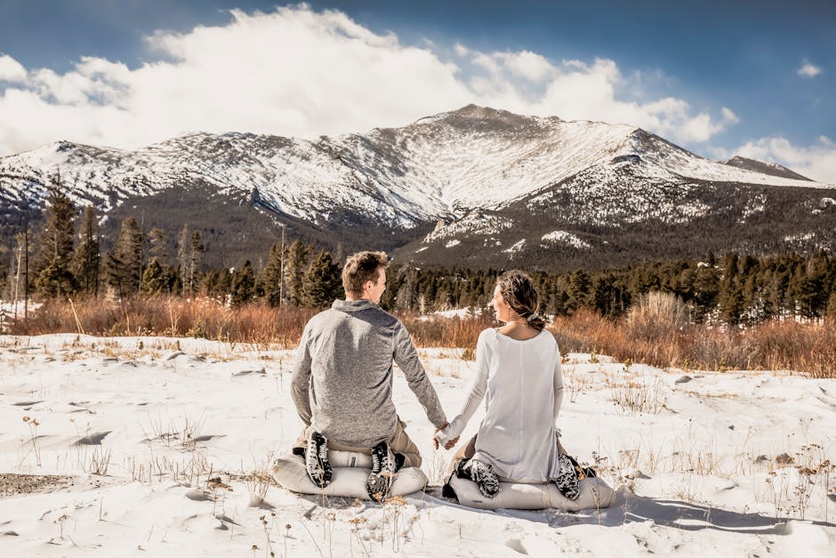 Couple sitting in snow, facing a scenic mountain view in Colorado, USA.
