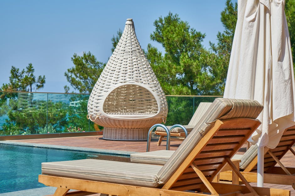 Elegant poolside setting featuring modern loungers and a unique woven chair in a tropical resort.