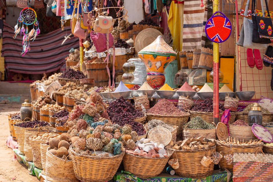Colorful market stall featuring a variety of spices, wicker baskets, and handmade crafts.