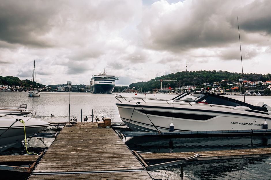 Vibrant marina in Sandefjord, Norway with boats and cruise ships under cloudy skies.
