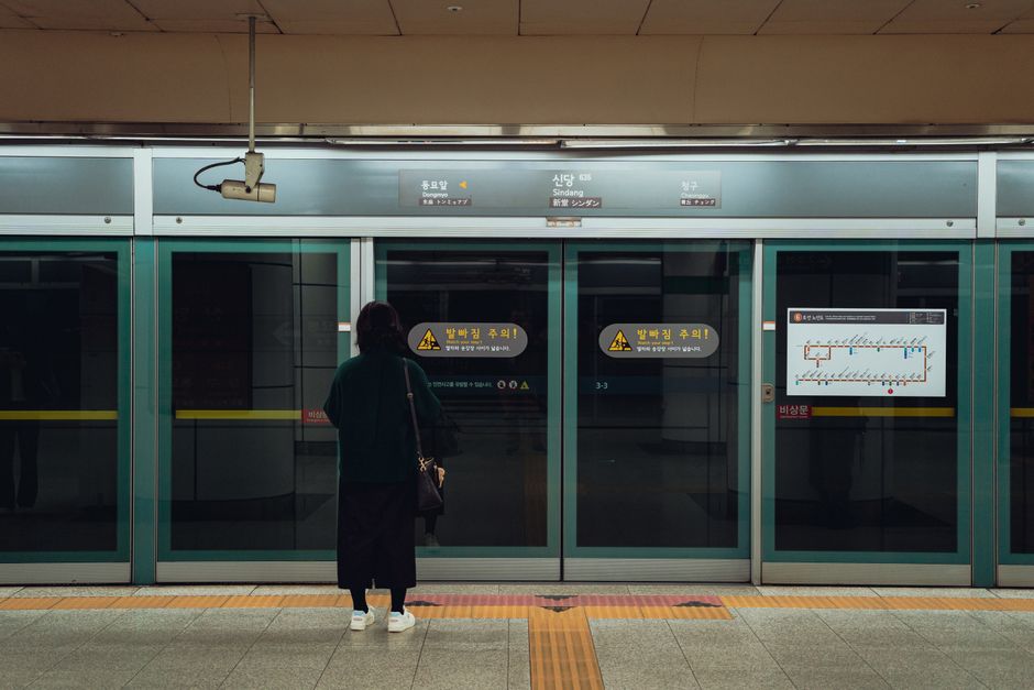 Individual waits at modern Suwon subway station in South Korea.