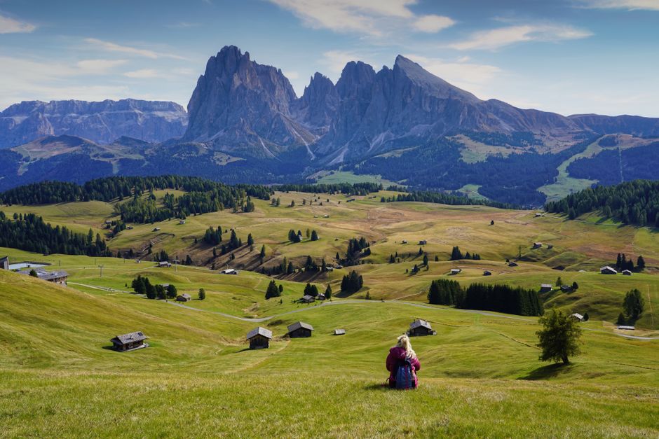 A woman enjoys the scenic view of the majestic Dolomites from a tranquil meadow.