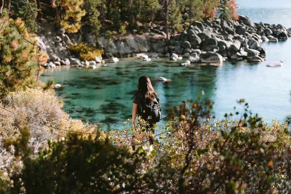 A woman hiking by the picturesque waters of South Lake Tahoe, capturing the essence of nature's beauty.