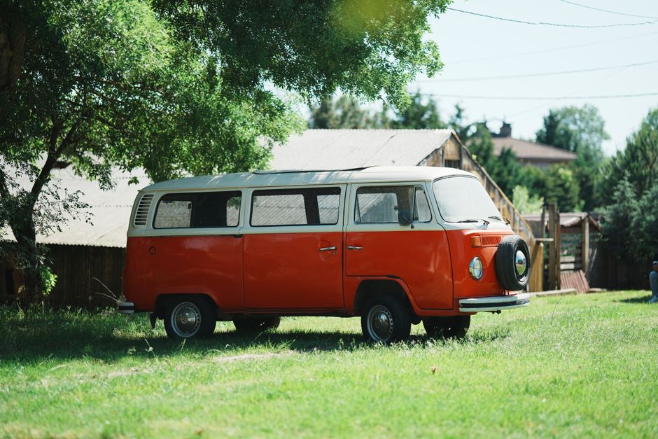Vintage orange camper van parked outdoors on a sunny day, evoking a sense of adventure and nostalgia.