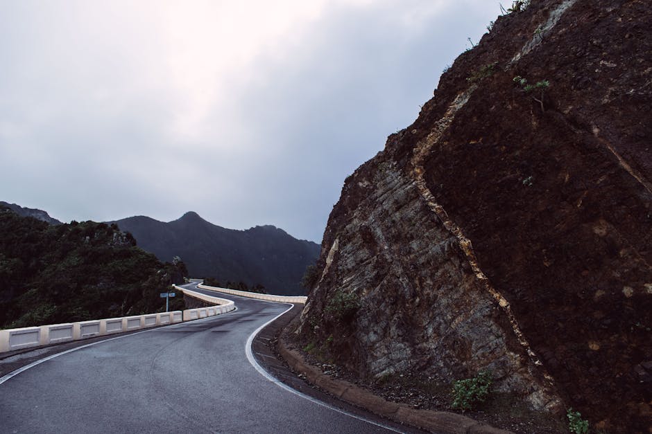 Scenic view of a winding road through mountains under a cloudy sky.