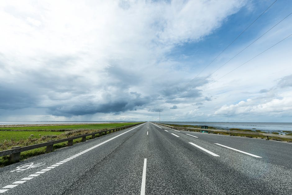 Long coastal road in Denmark with scenic views and dramatic sky, perfect for travel photography.