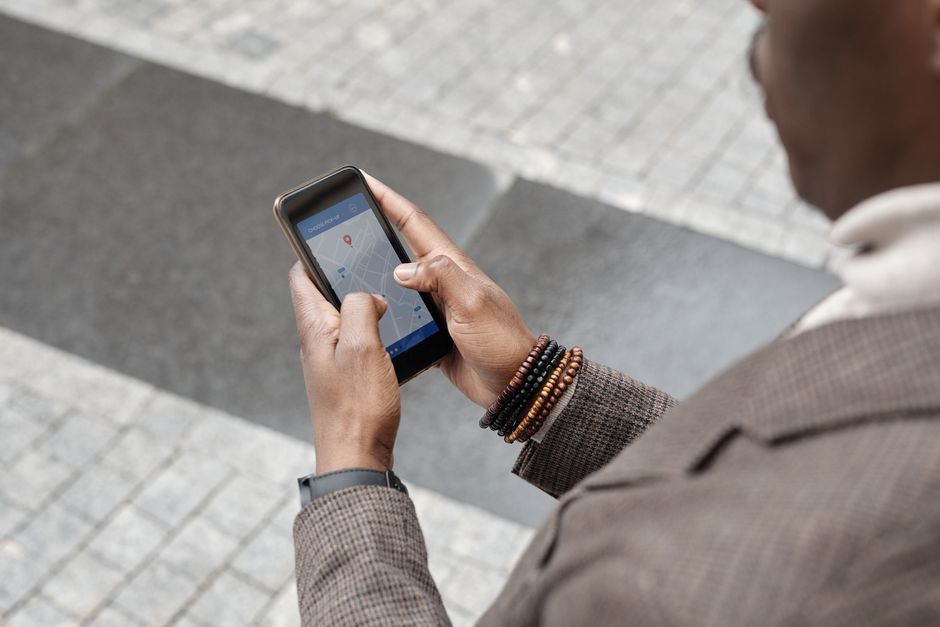 A stylish professional adult using a smartphone with a navigation app on an urban street.