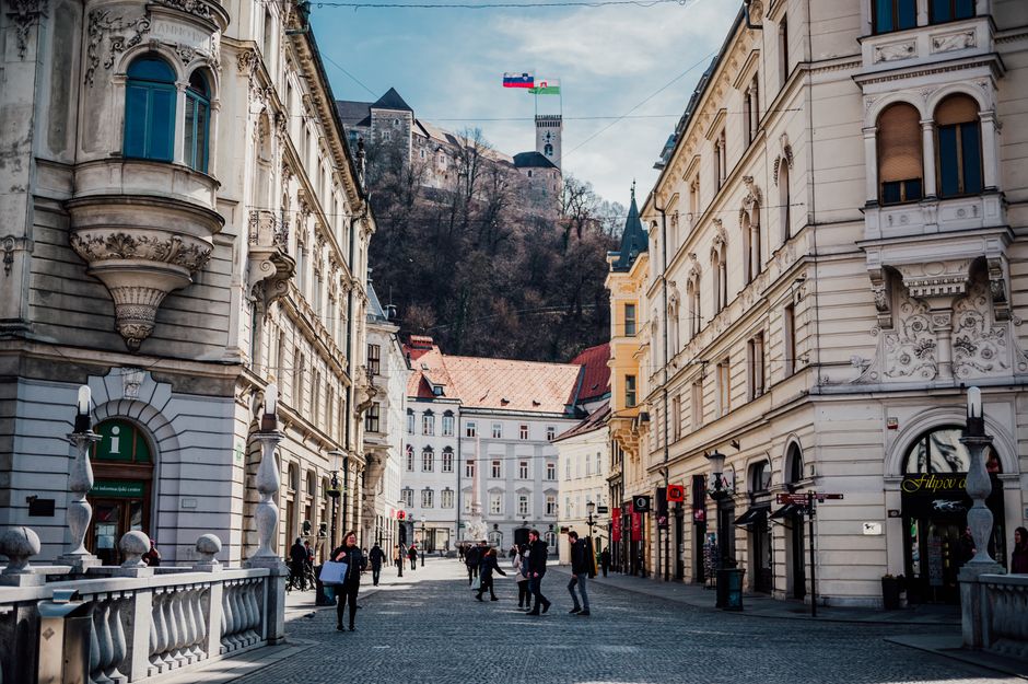 Stroll through a historic street in Ljubljana, Slovenia, with a view of the castle atop the hill.