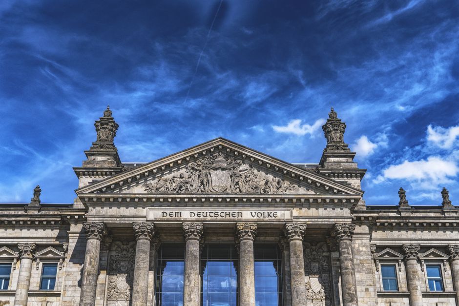 Low angle view of the iconic Reichstag building in Berlin with clear blue skies.