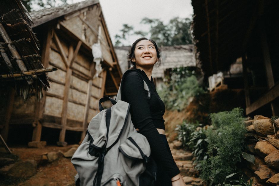An Asian woman backpacker smiles while exploring a traditional village in Banten, Indonesia.