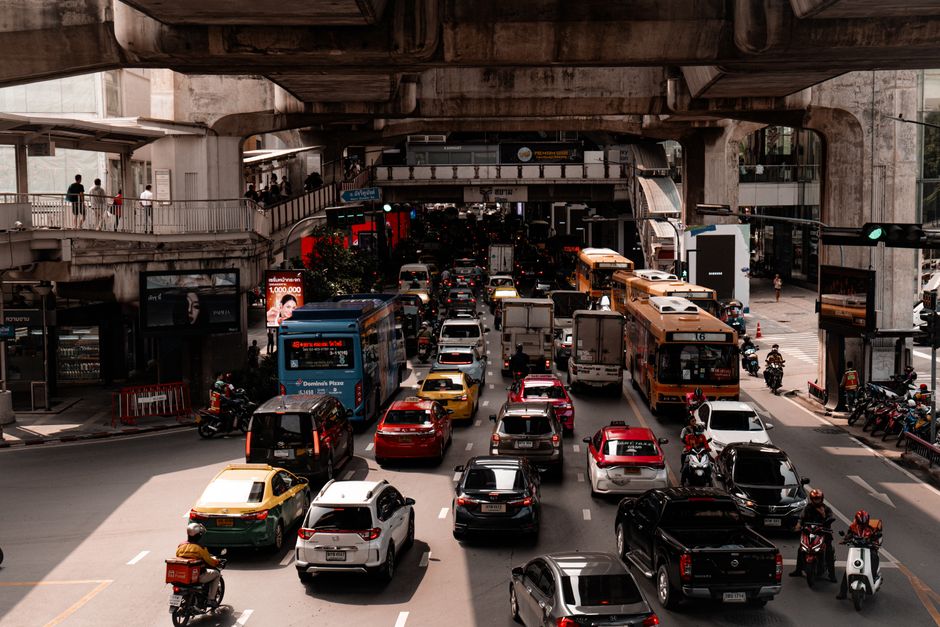 A busy traffic scene in downtown Bangkok, showcasing congestion under a flyover.