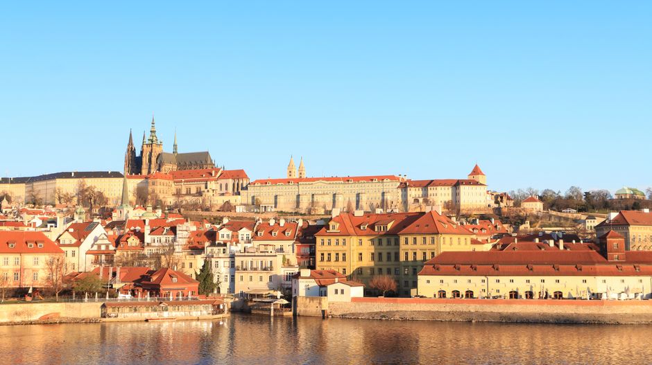 Beautiful panoramic view of Prague Castle and surrounding architecture under warm sunlight.