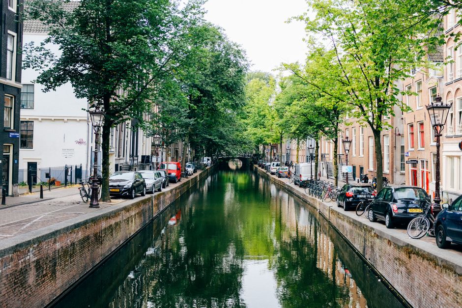 Perspective view of narrow old city alley with historic buildings along calm canal during sunny day
