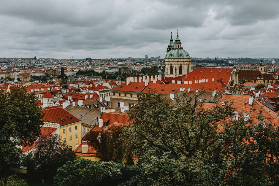 A picturesque view of Prague's iconic red rooftops and historical architecture under a cloudy sky.