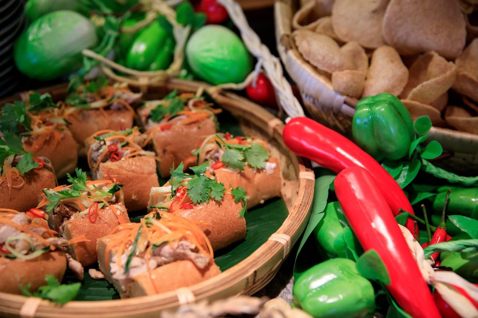 Colorful Vietnamese Banh Mi rolls surrounded by fresh vegetables, showcasing vibrant culinary presentation.